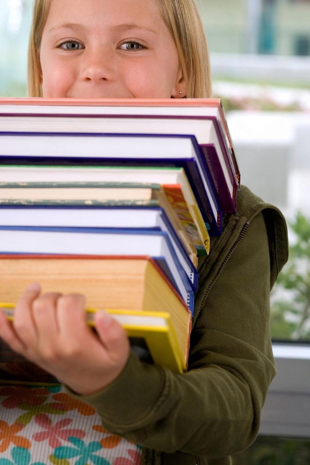 Young girl carrying a heavy pile of colourful school books